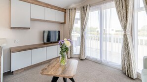 Una stanza moderna con televisione, una panca in legno e un vaso di fiori.