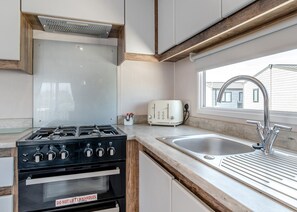 Una cocina moderna con estufa a gas, horno y ventana con vistas a una casa.