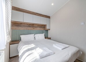 Un dormitorio con cama, cabecera de madera, mesita de noche y lámpara de pared.