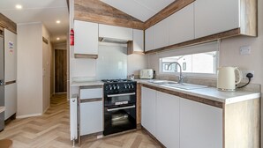 Una cucina compatta con piano cottura a gas, forno, lavello e finestra.