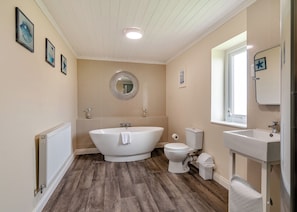 Ein Badezimmer mit freistehender Badewanne, Toilette, Waschbecken, Spiegel und Heizkörper.