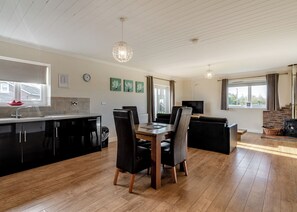 Eine moderne Küche mit Essbereich, ein Wohnzimmer mit Sofa und Fernseher sowie ein Kamin.