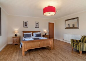 A bedroom with a wooden bed, bedside lamps, a red ceiling light, a mirror, and a radiator.
