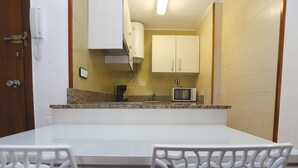 A compact kitchen with white cabinets, a microwave, and a coffee maker on the counter. - Cozy Apartment with Terrace Near Capellans Beach, Salou (Salou)