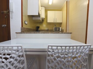 A compact kitchen with white cabinets, a microwave, and a coffee maker on the counter.