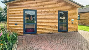 A log cabin with two glass doors, a brick pathway, and a grassy area. - 3 bedroom accommodation in Flaxton (Flaxton)