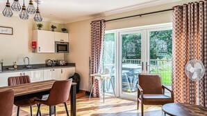 A modern kitchen with a microwave, sink, and cabinets. There is a dining area with a wooden table and chairs. A sliding glass door leads to an outdoor patio with a table and chairs. - 3 bedroom accommodation in Flaxton (Flaxton)