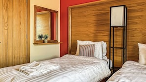 A hotel room with two beds, a wooden wardrobe, a mirror, and a bedside table with a plant. - 3 bedroom accommodation in Flaxton (Flaxton)
