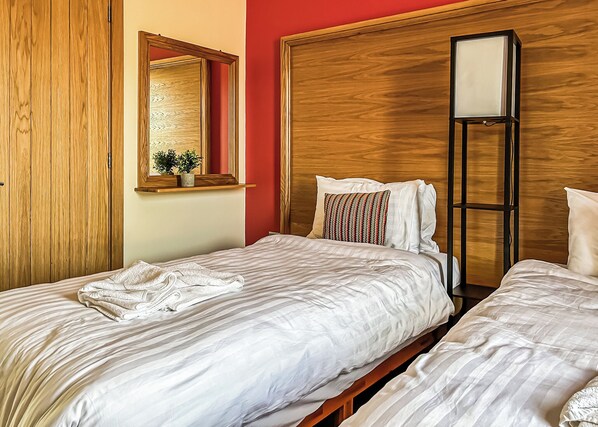 A hotel room with two beds, a wooden wardrobe, a mirror, and a bedside table with a plant. - 1 bedroom accommodation in Flaxton (Flaxton)