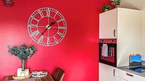 A red-walled room with a wooden dining table, chairs, a white cabinet, and a wall clock. - 3 bedroom accommodation in Flaxton (Flaxton)