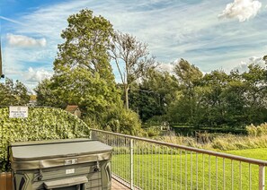 A hot tub with a warning sign, surrounded by lush greenery and a clear sky.