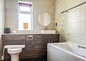 A bathroom with a toilet, a sink, a bathtub, a mirror, and a window with a view.