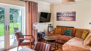 A living room with a sofa, chairs, a TV, a fan, and a painting. - 3 bedroom accommodation in Flaxton (Flaxton)