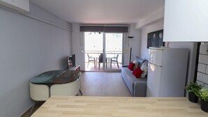 Un espacio habitable moderno y funcional con kitchenette, comedor y balcón.