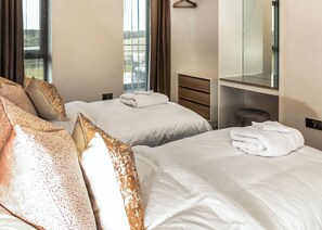 A hotel room with two beds, a bathroom, and a view of the outside.