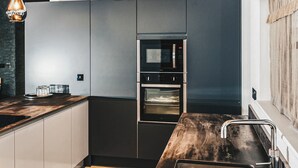 Une cuisine moderne dotée d’un four encastré, d’un four à micro-ondes et d’un plan de travail en bois.