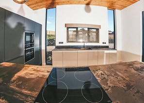 A modern kitchen with a built-in oven, a large window, and a unique black countertop.