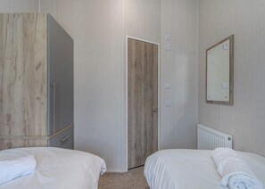 Un dormitorio con dos camas, un armario, una puerta, un espejo y un radiador.