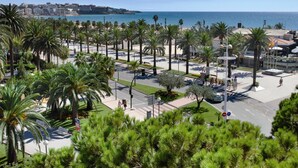Un paisaje urbano costero con palmeras, una playa y un puerto deportivo.