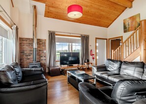 A living room with leather sofas, a TV, a fireplace, and a wooden ceiling.