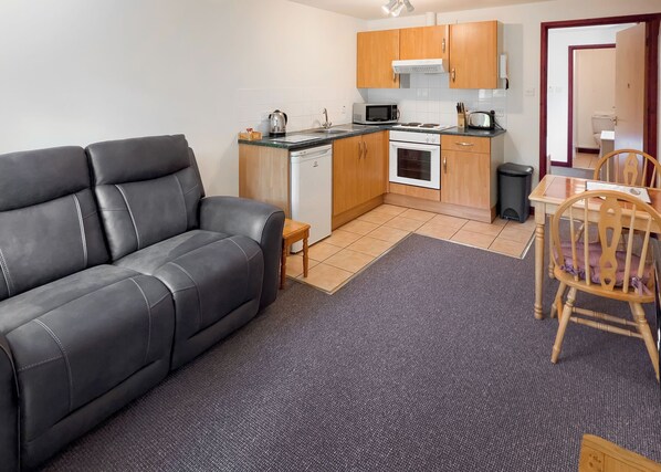 A compact living space with a sofa, kitchenette, and dining area. - Cottage with one double. (St Clears)