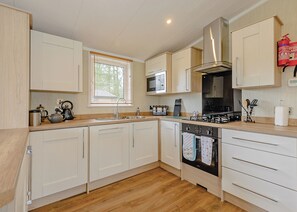 A modern kitchen with white cabinetry, a stainless steel stove, and a microwave.