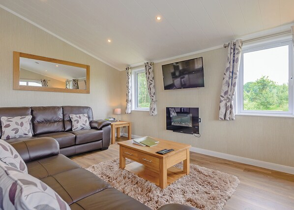 A living room with a sofa, a coffee table, a TV, and a window with curtains.