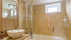 A bathroom with a large white sink, a glass-enclosed shower, a bathtub, and a window above the bathtub. - Lakeview 3 Pet Friendly (Woodhall Spa)