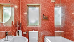 Un baño con lavabo, inodoro y bañera, un espejo y una ventana.