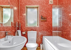 A bathroom with a sink, toilet, and bathtub, a mirror, and a window.