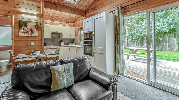 Un interior de madera con comedor, cocina y puertas de cristal correderas que dan a un patio exterior.