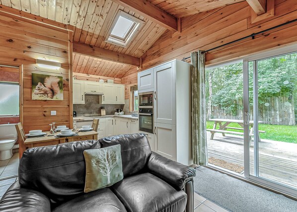 A wooden interior with a dining area, kitchen, and sliding glass doors leading to an outdoor patio.