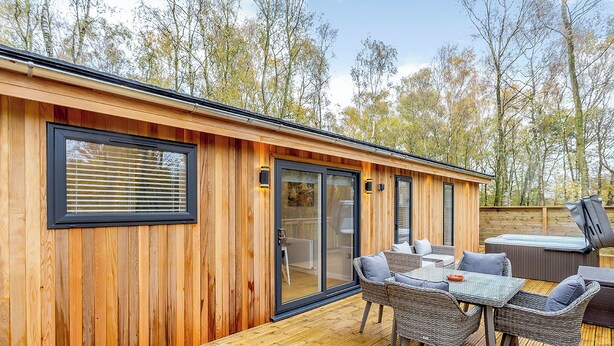 A wooden cabin with a deck, outdoor seating, and a hot tub. - 2 bedroom accommodation in Haddon (Haddon)