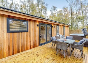 Une cabane en bois dotée d’une terrasse, d’un espace salon extérieur et d’un jacuzzi.