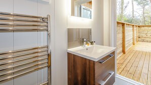 A modern bathroom with a large mirror, a white sink, and a wooden deck visible through the window. - 2 bedroom accommodation in Haddon (Haddon)