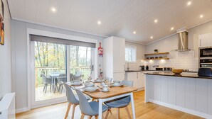 A modern kitchen with a dining area, wooden flooring, and a view through a sliding glass door. - 2 bedroom accommodation in Haddon (Haddon)