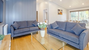 A modern living room with two grey sofas, a glass coffee table, and a potted plant. - 2 bedroom accommodation in Haddon (Haddon)