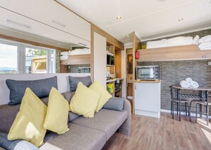 Un intérieur de camping-car compact comprenant un canapé, un coin cuisine et un espace repas.