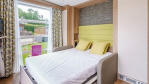 A bedroom with a bed, curtains, a window, and a view of the outside.