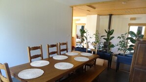 Un área de comedor con una mesa y sillas de madera, rodeada de plantas en macetas.
