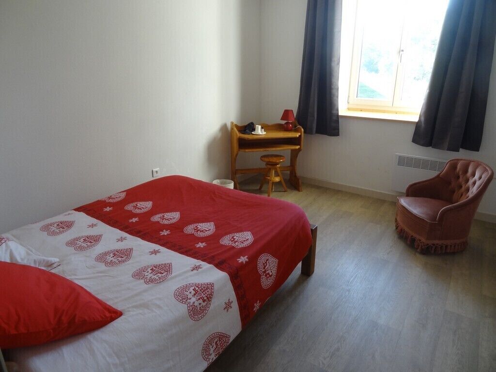 A room with a bed, a desk, a chair, and a window with curtains.