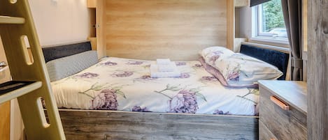 Ein Schlafzimmer mit Bett, Holz-Kopfteil und einem Fenster mit Vorhängen.