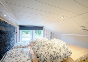 A bedroom with a sloped ceiling, a large window, and a view of the outdoors. - 1 bedroom accommodation in Newcastleton, (Newcastleton,)