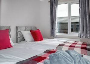 Une chambre à coucher avec un lit, une fenêtre avec des rideaux et un radiateur.