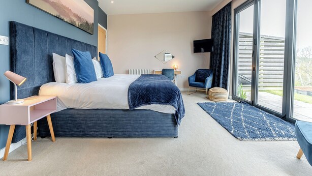 Une chambre moderne avec un grand lit, une table de chevet, une chaise et un téléviseur.