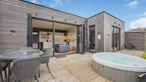 Une maison moderne dotée d’un patio, d’un jacuzzi et d’un coin repas aménagé avec des meubles en osier.
