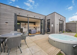 A modern house with a patio, a hot tub, and a dining area with wicker furniture. - Woodland View Retreat (Lewes)