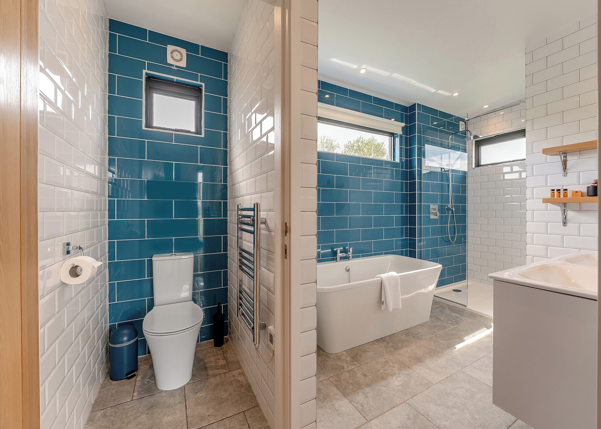 Une salle de bain avec des carreaux bleus et blancs, des toilettes, une baignoire et une douche.