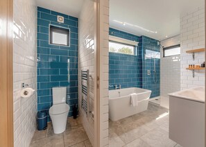 A bathroom with blue and white tiles, a toilet, a bathtub, and a shower. - Woodland View Retreat (Lewes)