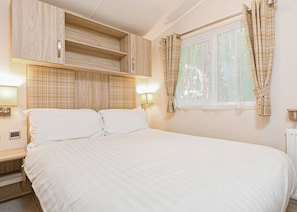 Un dormitorio con cama, armario de madera, lámparas de noche y una ventana con cortinas.